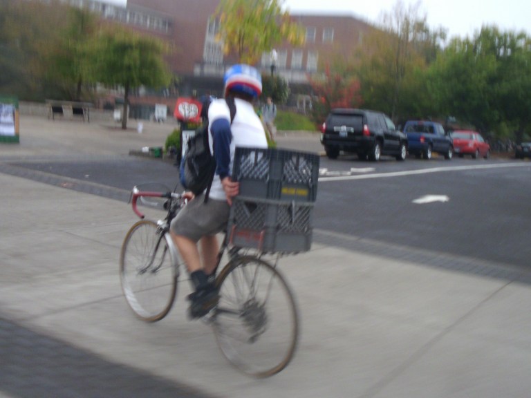 Domestique hard at work earning his paycheck A cyclist on a crate bike carrying a secon crate